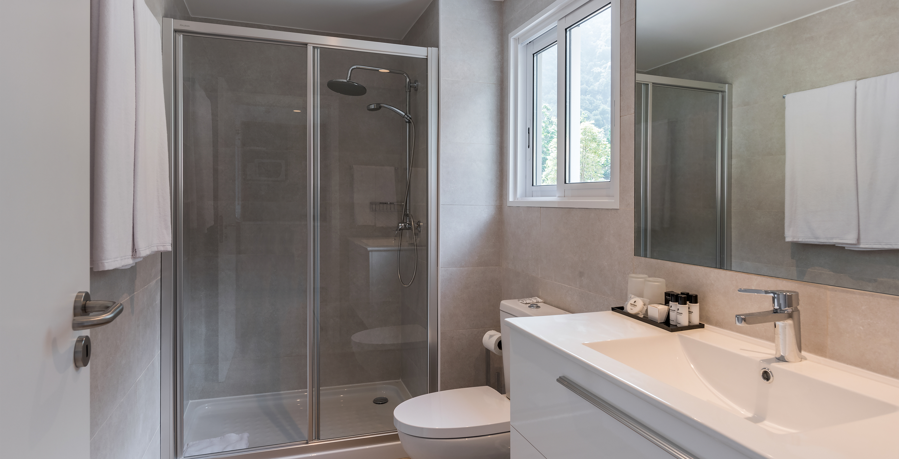 L'Étude - Vue jardin du Pestana Quinta do Arco a salle de bain avec douche, toilettes, lavabo avec grand miroir et fenêtre