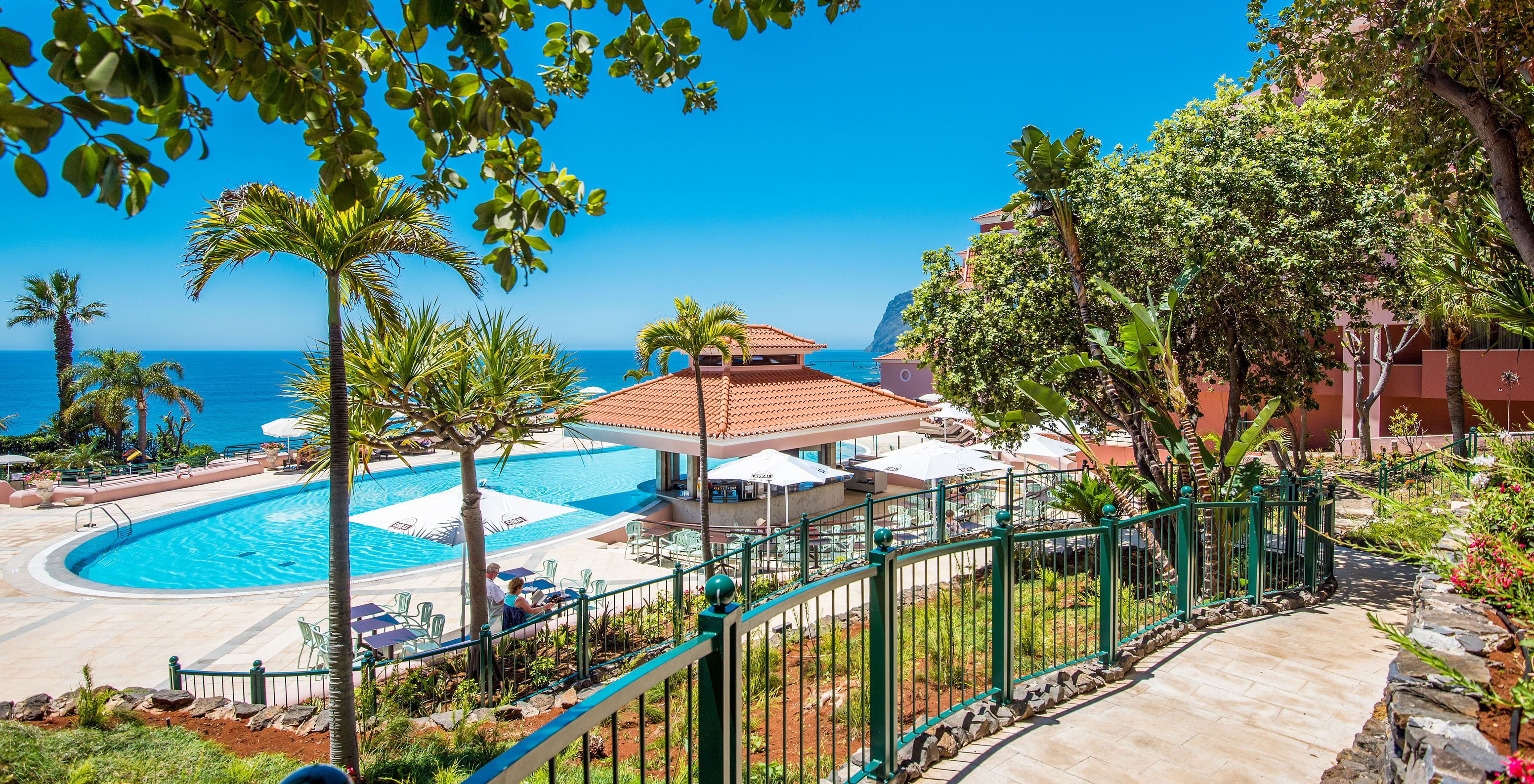 Le Sunset Pool Bar, à l'Hôtel 5 étoiles tout compris à Funchal, près de la piscine, a des tables et des parasols