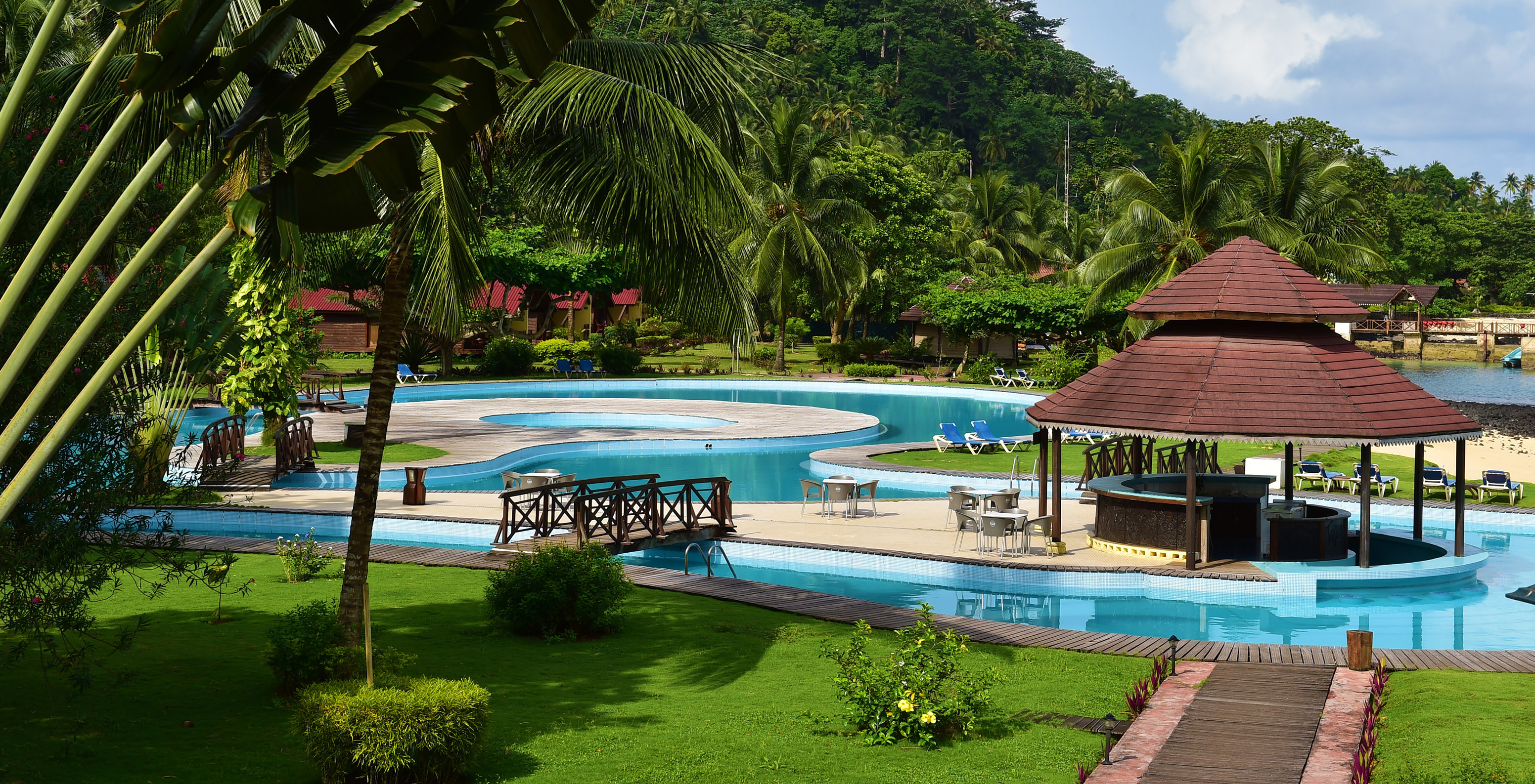 Piscine extérieure face à la plage, entourée de végétation dans un cadre paradisiaque