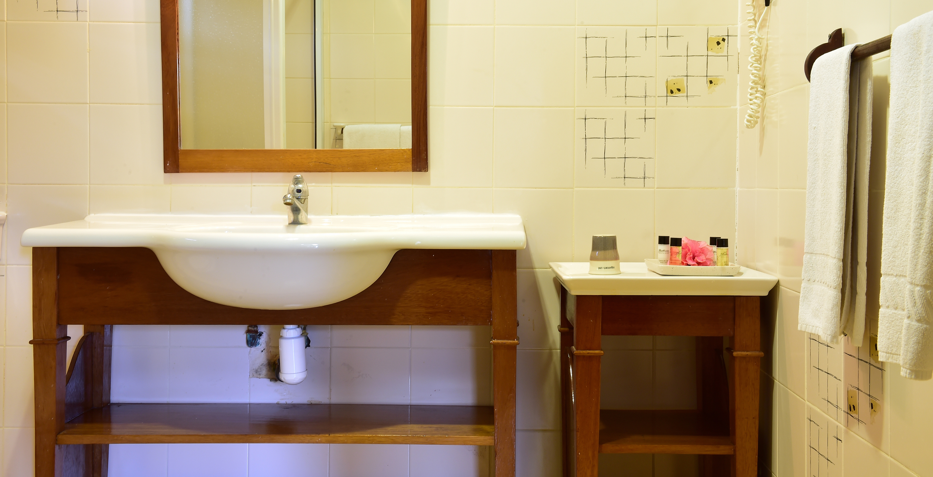 La Suite Standard du Pestana Equador Ilheu das Rolas a une salle de bain avec une table et un lavabo avec miroir