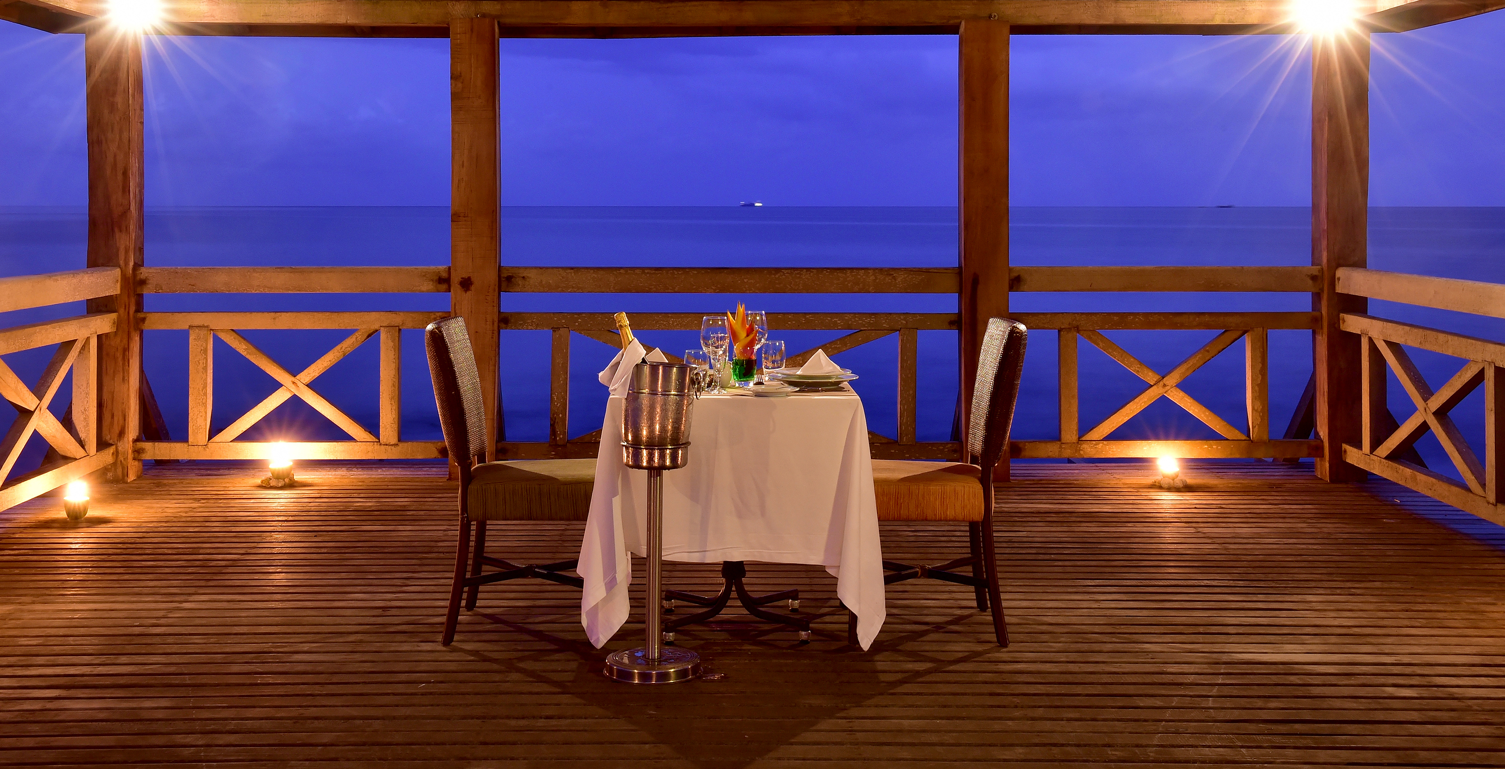 Table préparée pour un dîner romantique à deux sur le ponton en bois sur la mer du Pestana São Tomé