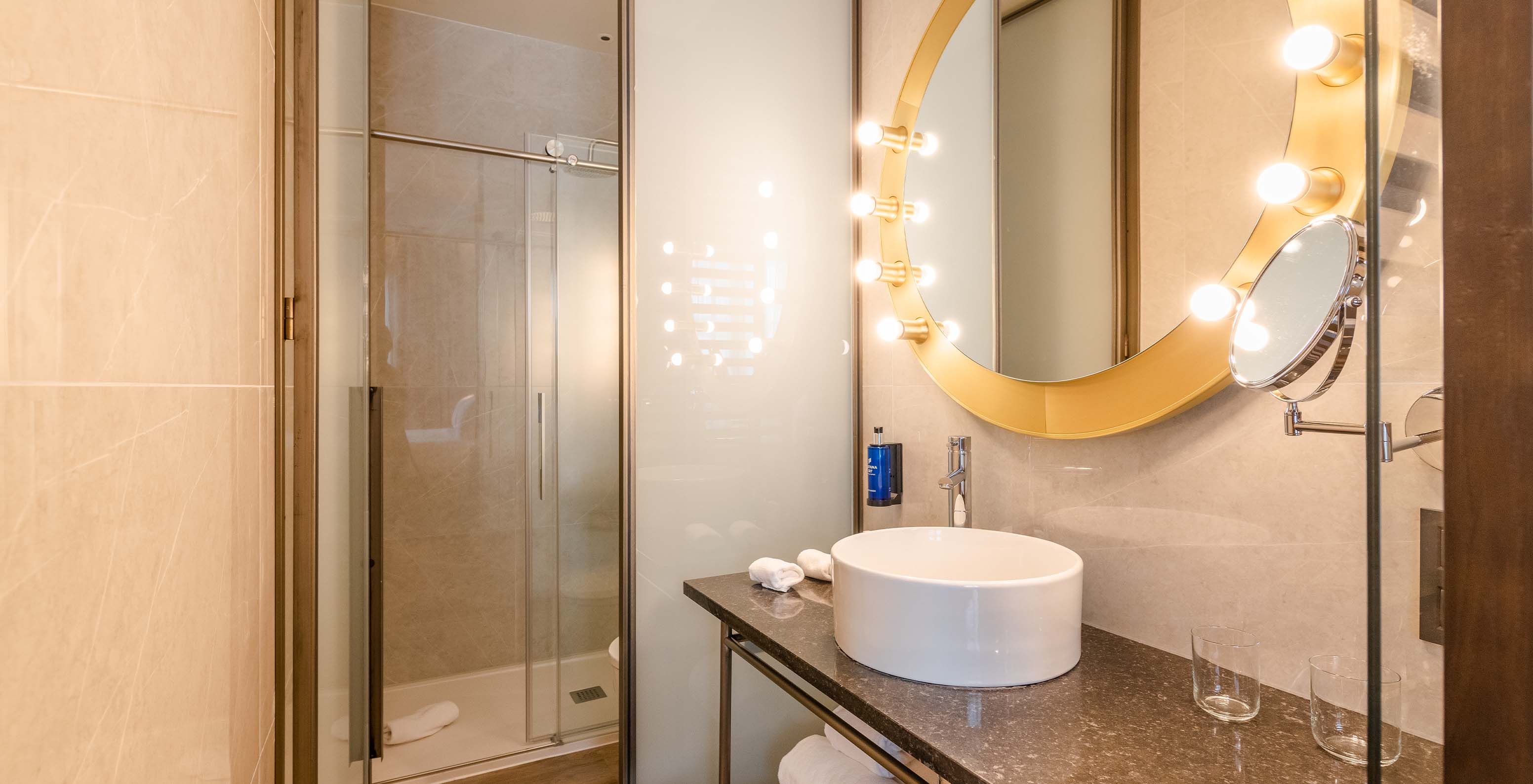 Le Premium avec Vue du Pestana CR7 Gran Vía Madrid a une salle de bain avec miroir rond et douche avec portes coulissantes