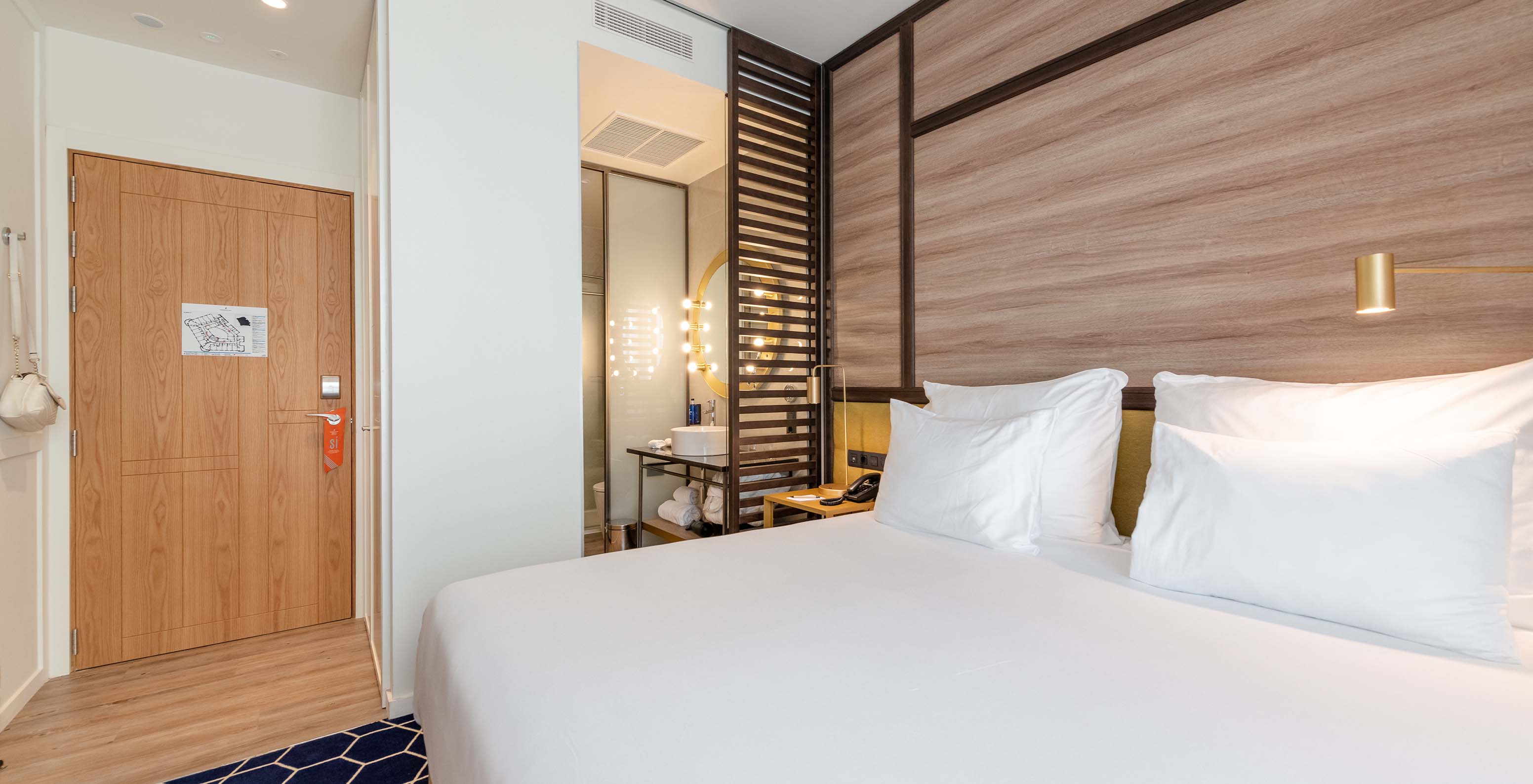 Le Premium avec balcon du Pestana CR7 Gran Vía Madrid a un lit double, une séparation en bois et un miroir lumineux