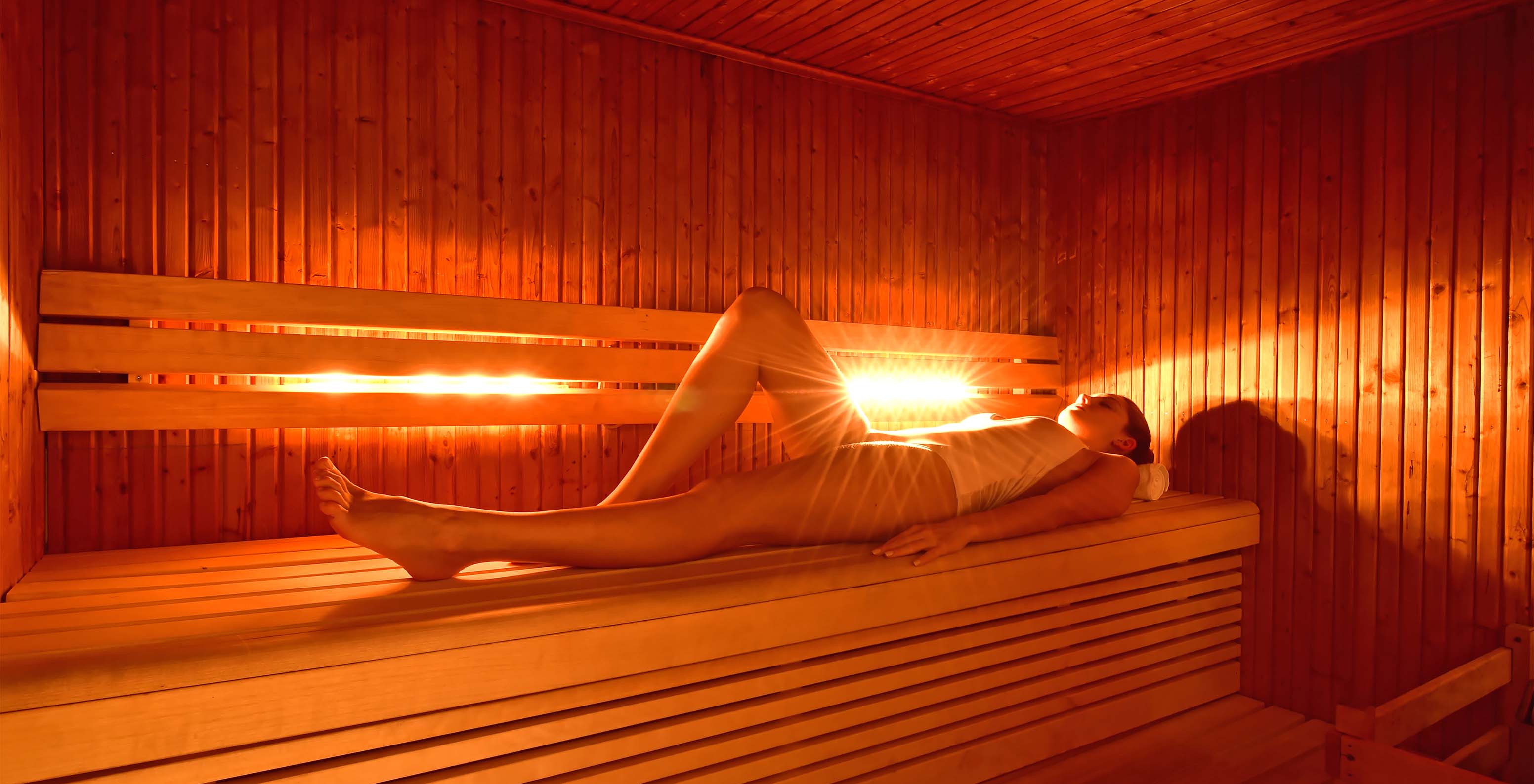 SPA de l'hôtel Pestana Chelsea Bridge avec une dame allongée dans le sauna se détendant, avec lumières oranges