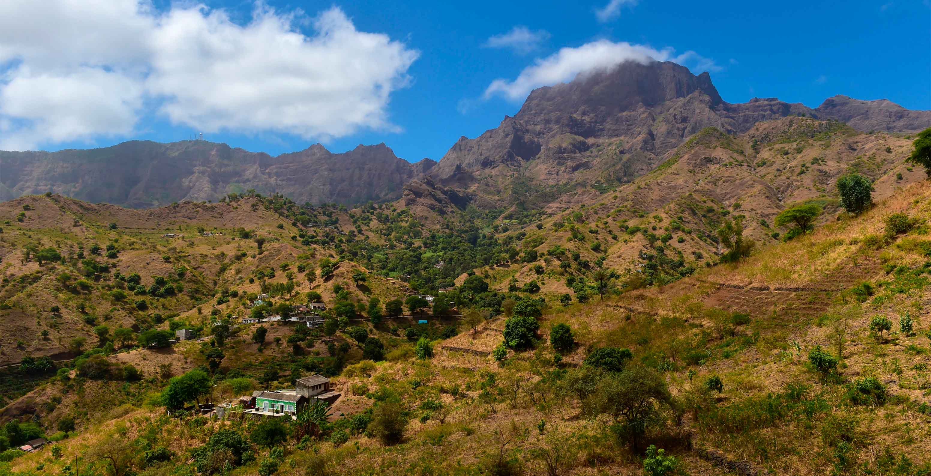 Uitzicht op een berg in Kaapverdië, bedekt met veel groen en een klein dorp met geïsoleerde huizen