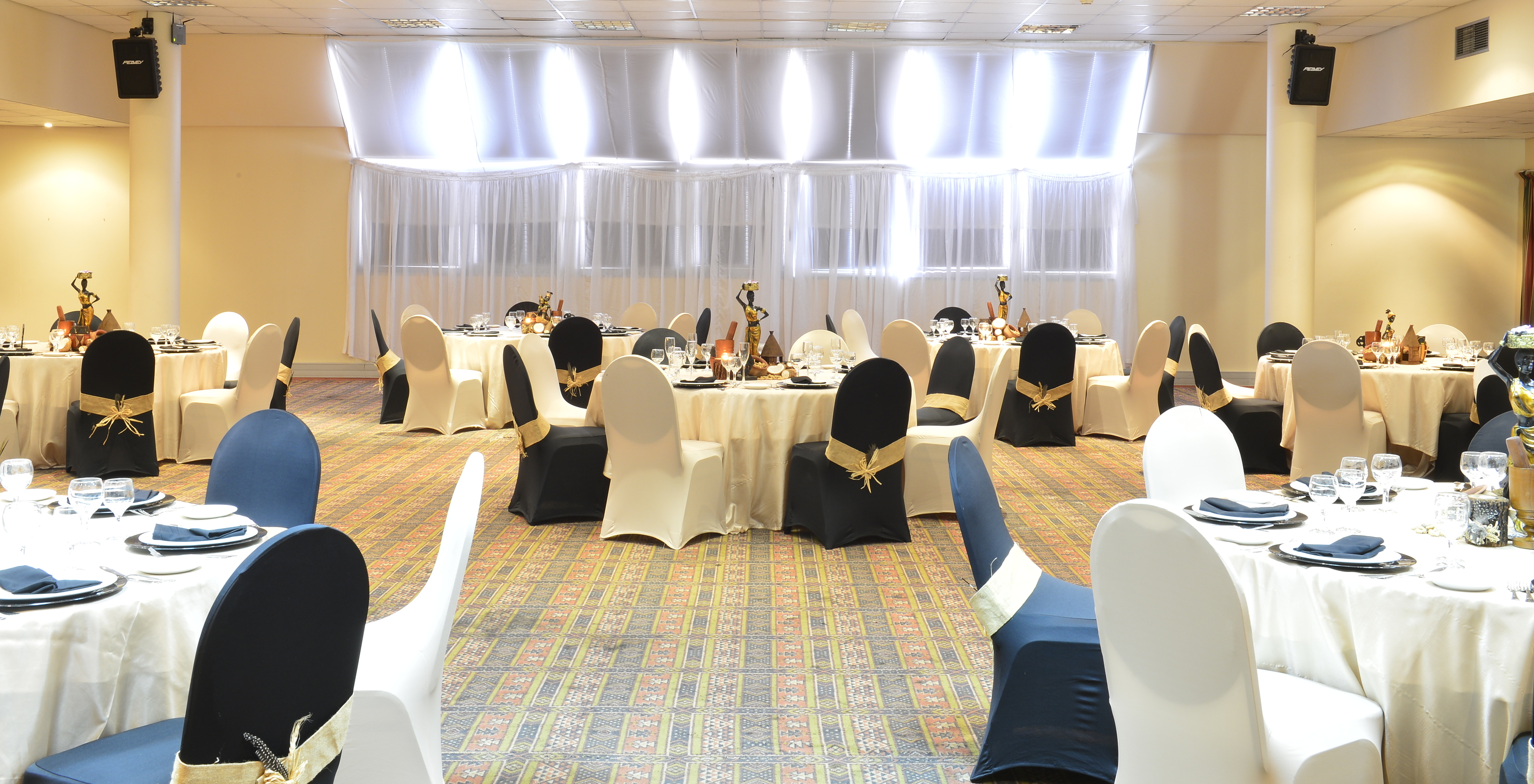 Evenementenzaal in hotel in Maputo met tafels, stoelen en luidsprekers voor een groep