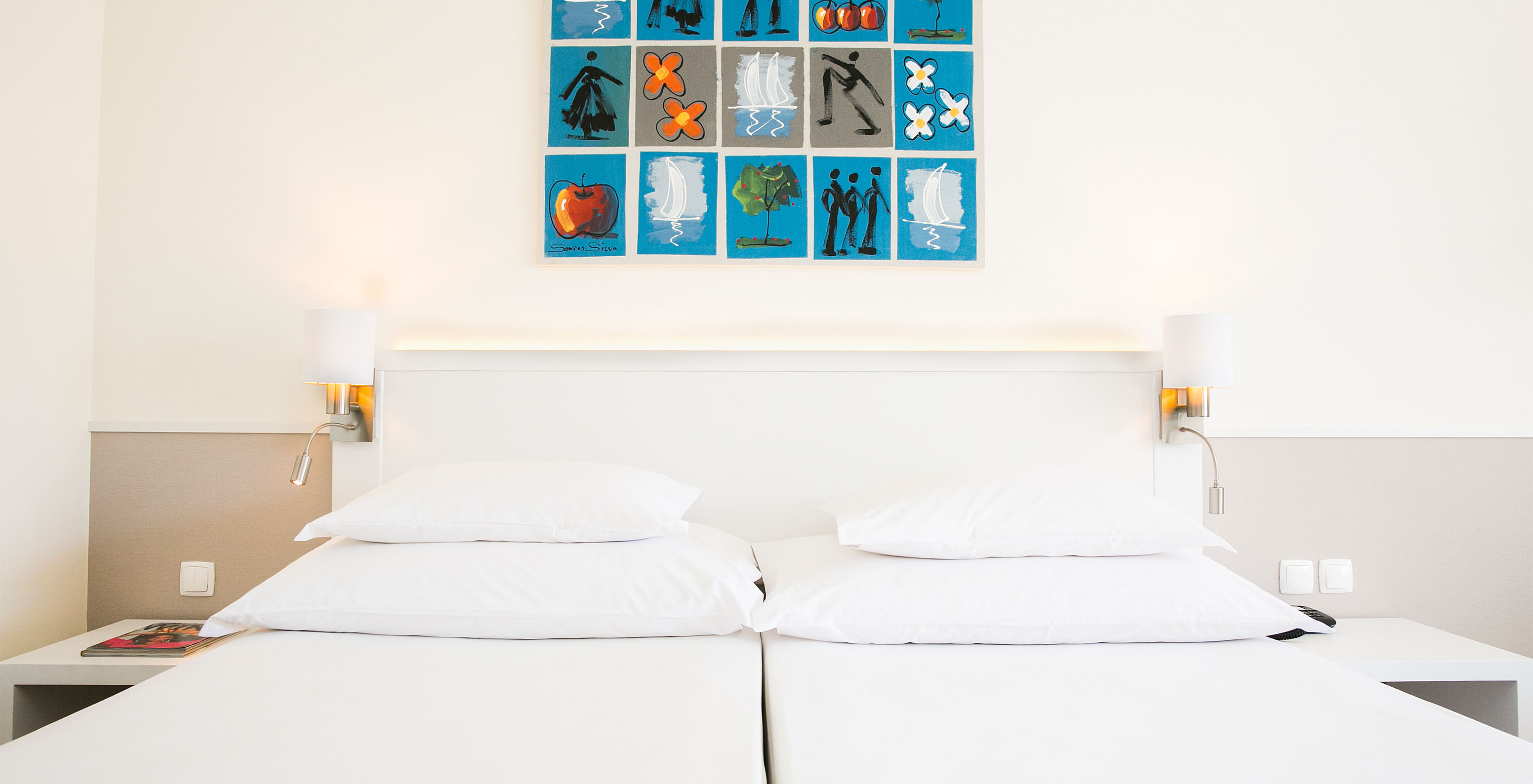 De Deluxe kamer van Pestana Cascais heeft twee eenpersoonsbedden, nachtkastje met lamp en een schilderij aan de muur