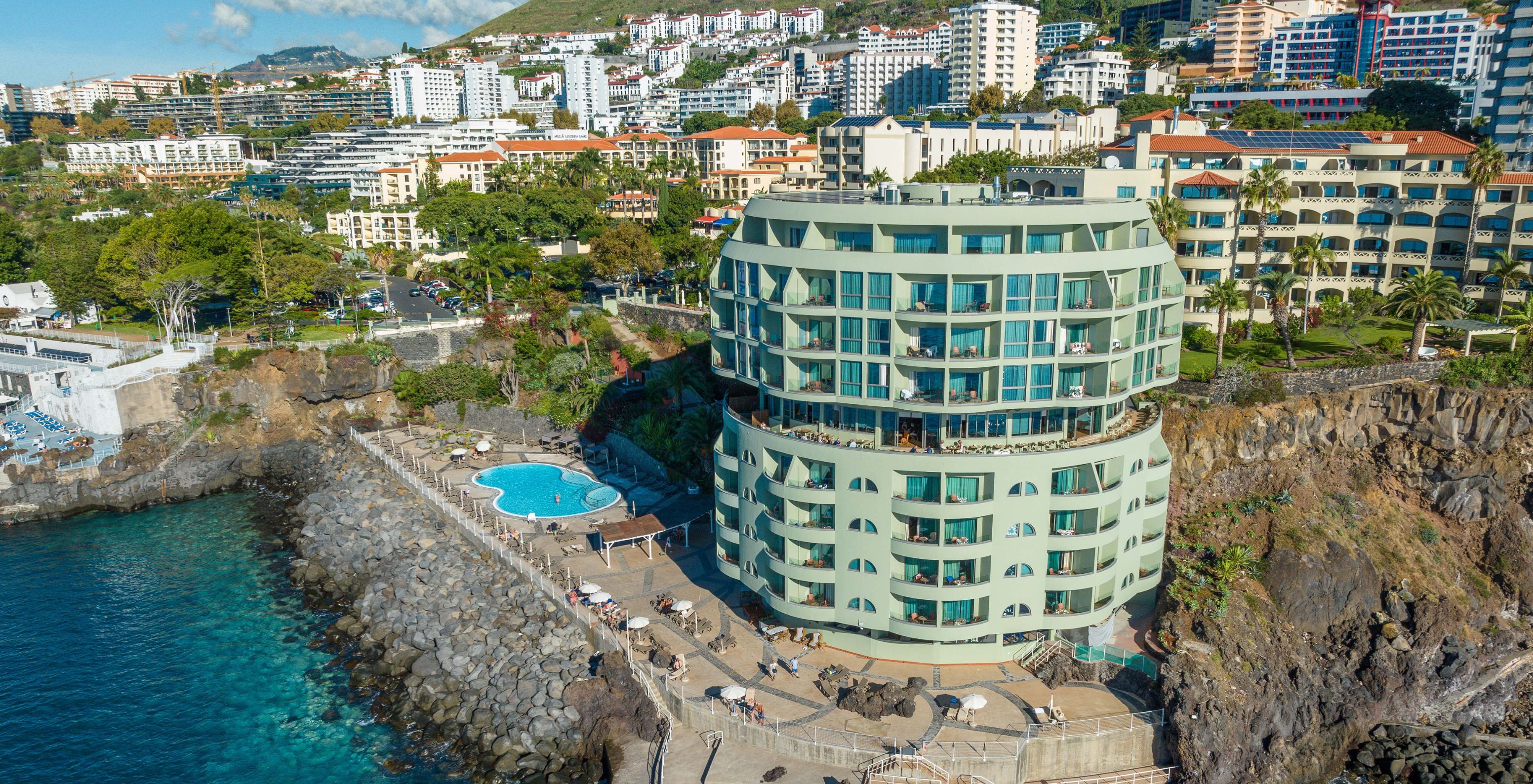 Uitzicht op Pestana Vila Lido Madeira, een gebouw met buitenzwembad, ligbedden en directe toegang tot de zee