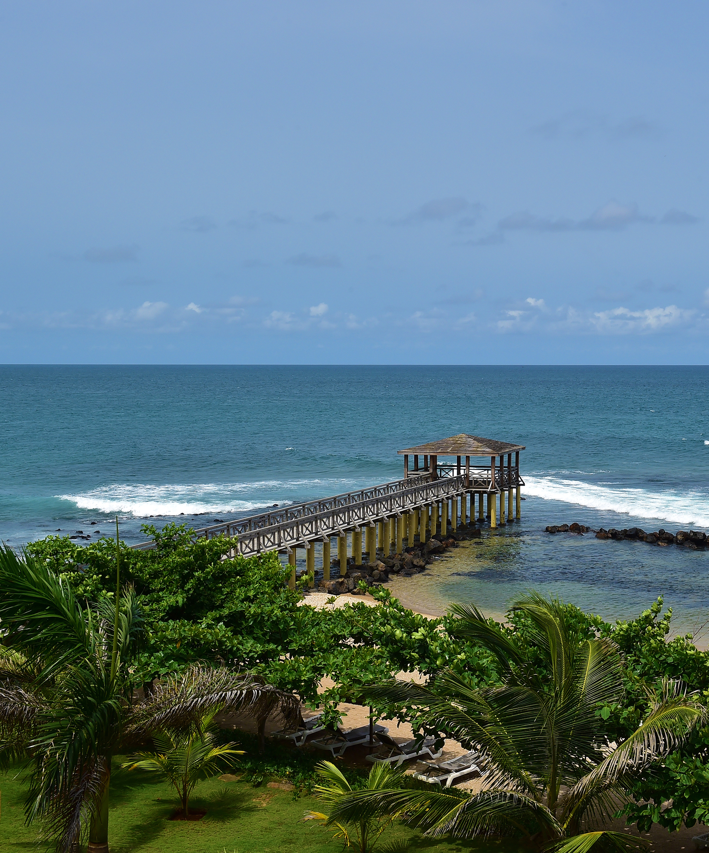 Panoramisch uitzicht op privéstrand van Pestana São Tomé met houten pier over helder baaiwater Ana Chaves