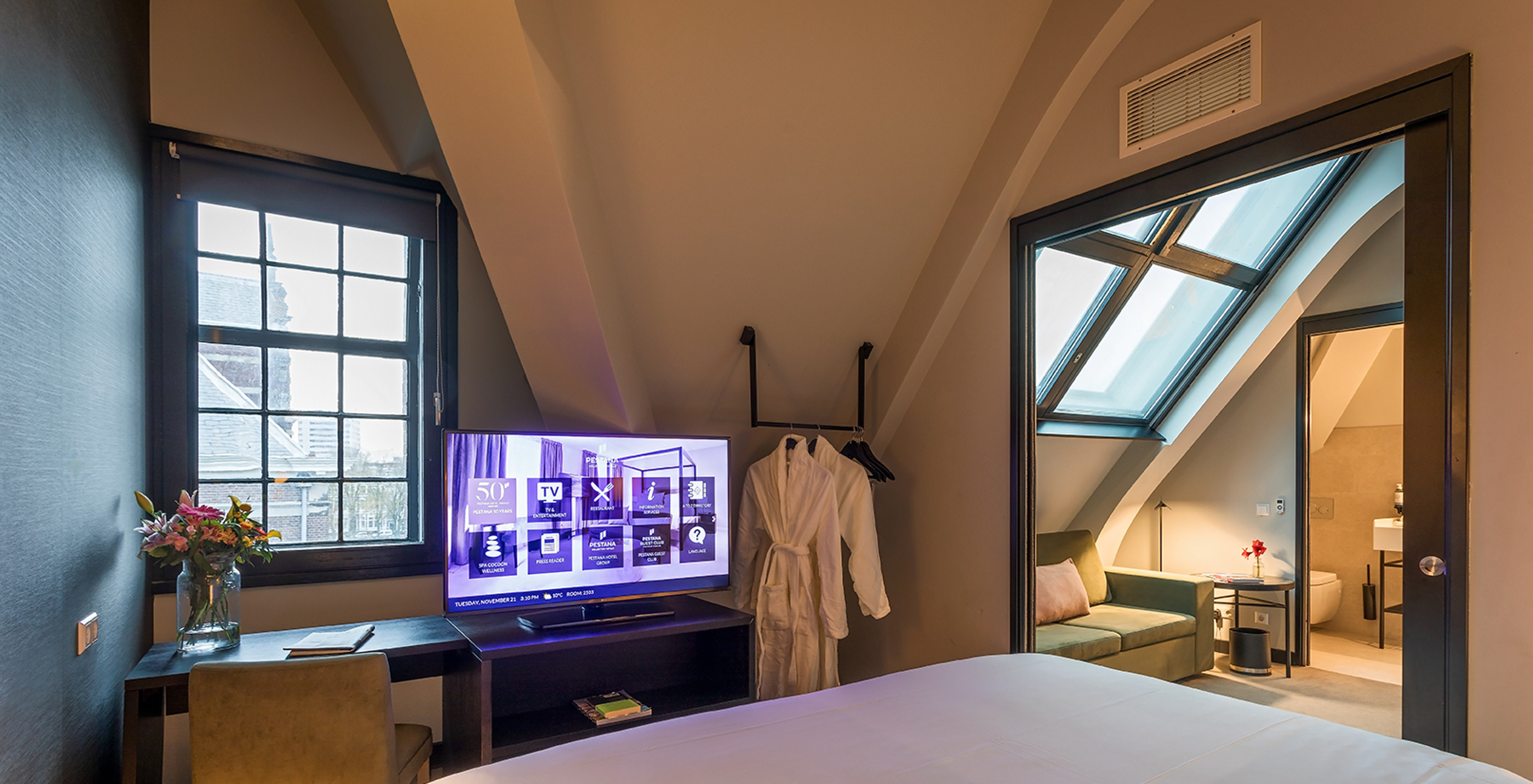 Loft kamer Pestana Amsterdam Riverside heeft groene bank, salontafel en twee badjassen