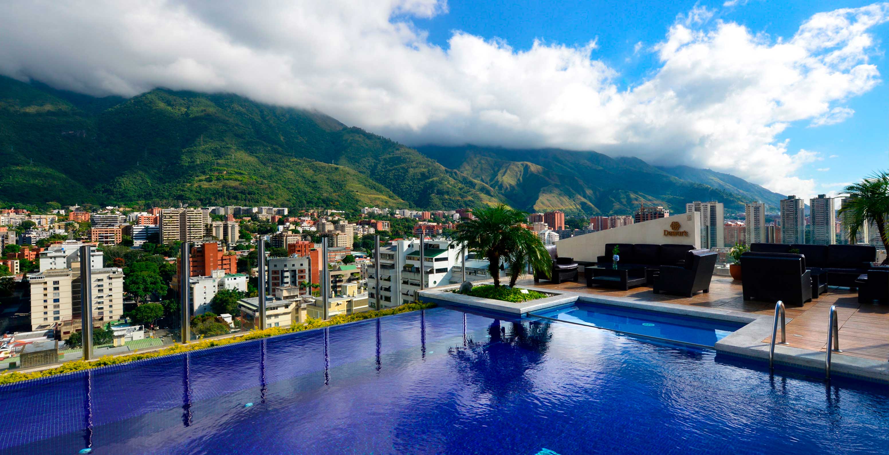 Zwembad op het dakterras van het hotel in Caracas met uitzicht op de stad en bergen op de achtergrond