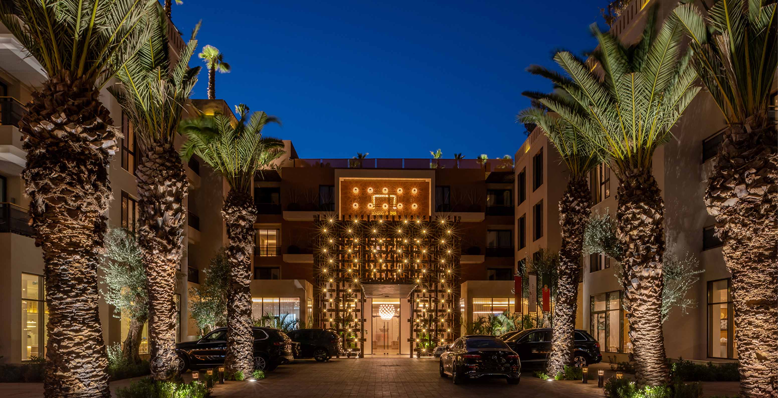 Entrada do Pestana CR7 Marrakech, com uma fachada com luzes e decoração típica marroquina e várias palmeiras iluminadas