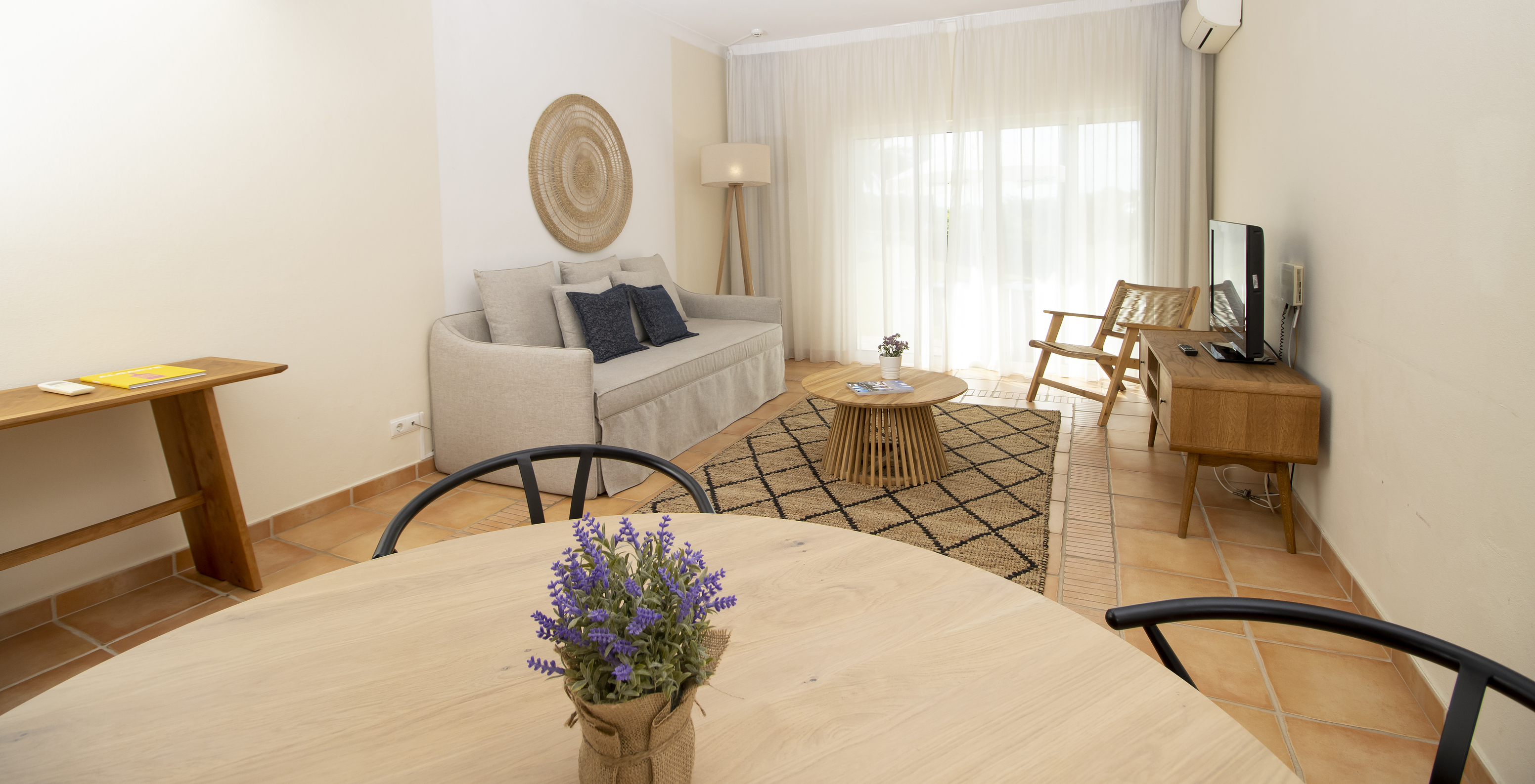 O Apartamento T2 Superior do Pestana Palm Gardens tem uma sala com uma mesa redonda, sofá, televisão e janela para o jardim