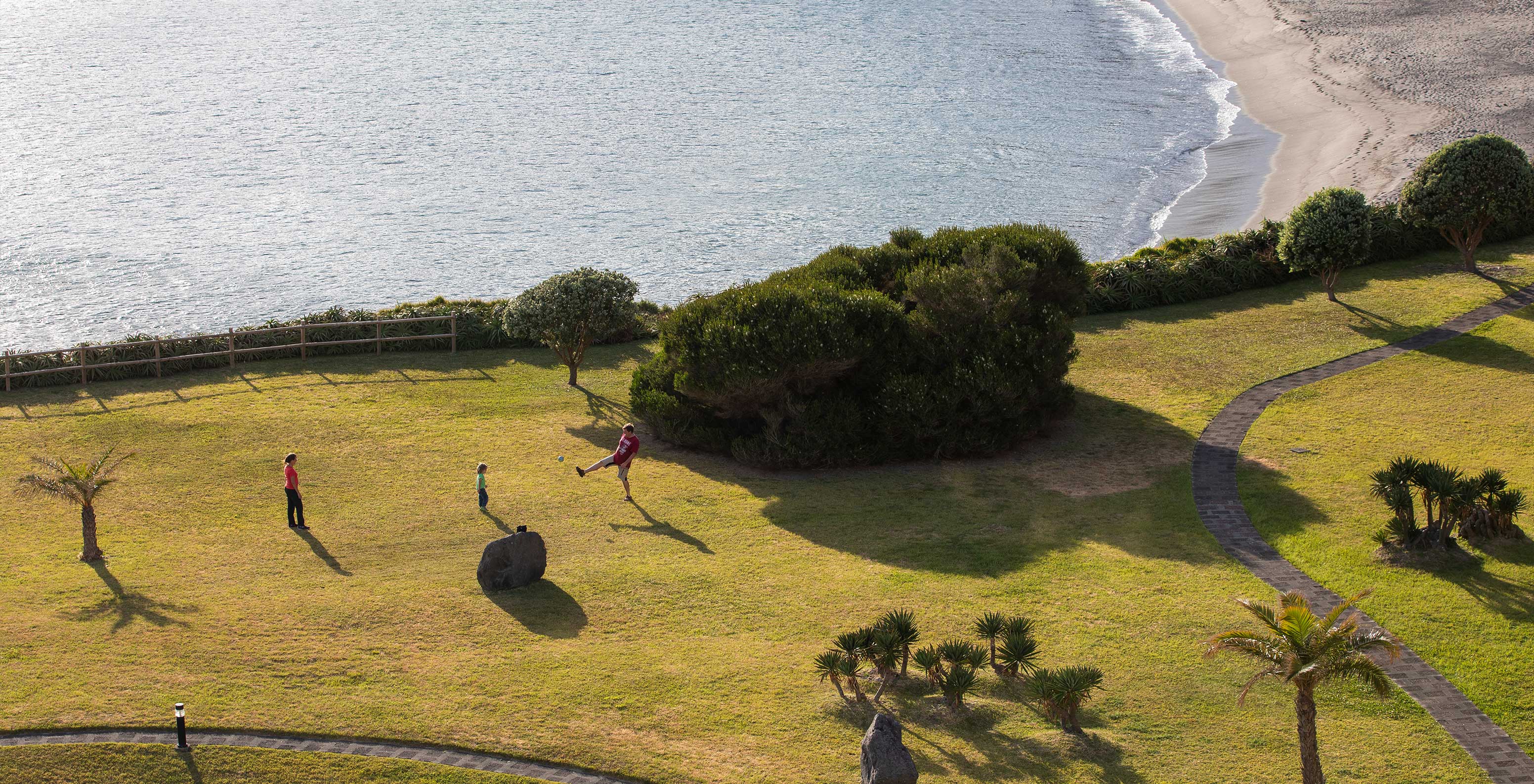 Uma família joga à bola nos jardins do resort de 4 estrelas nos Açores, no meio dos jardins do hotel, com vista para o mar