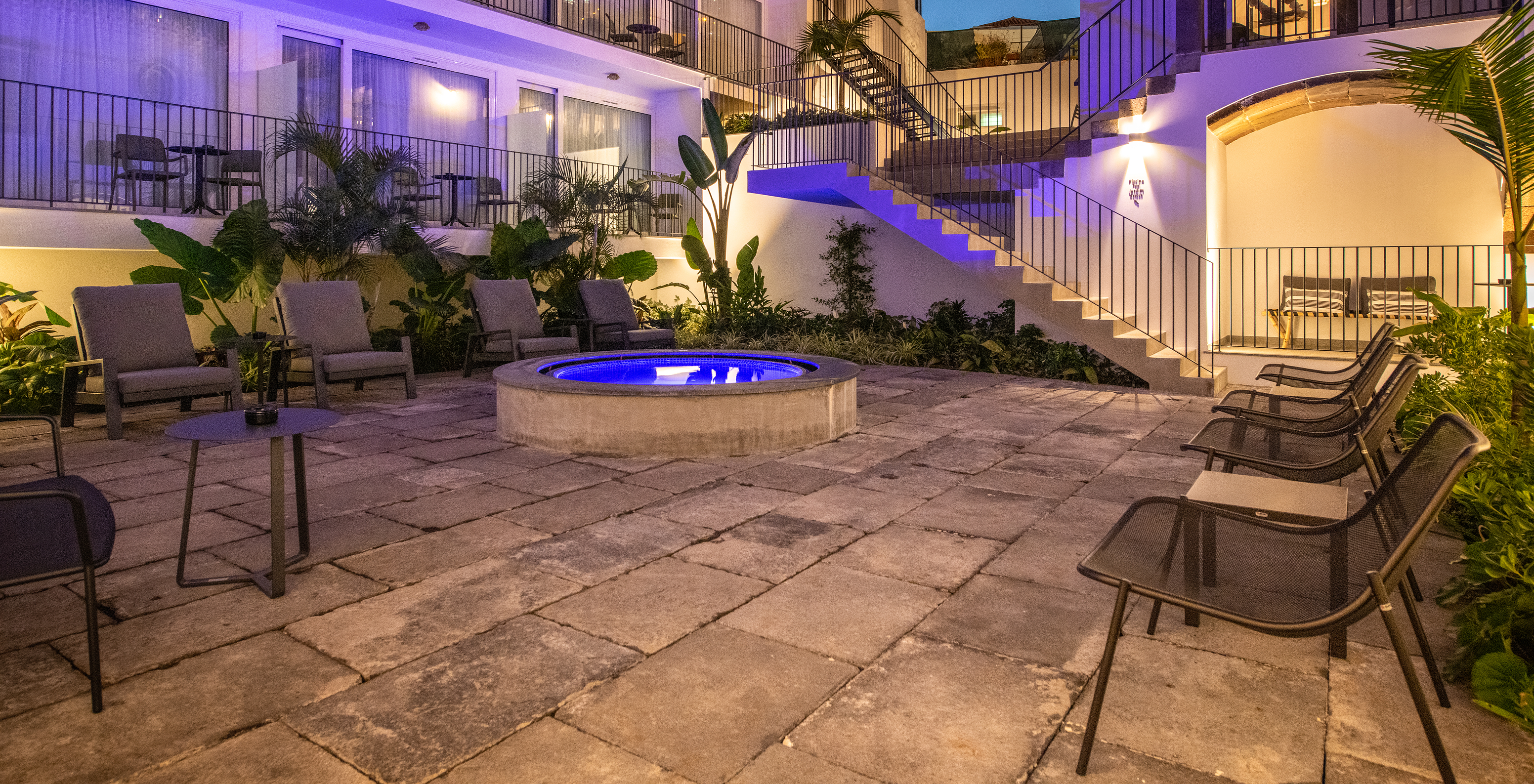 Pátio interior de noite do Hotel em Câmara de Lobos, na Madeira, com várias plantas, varandas e uma esplanada