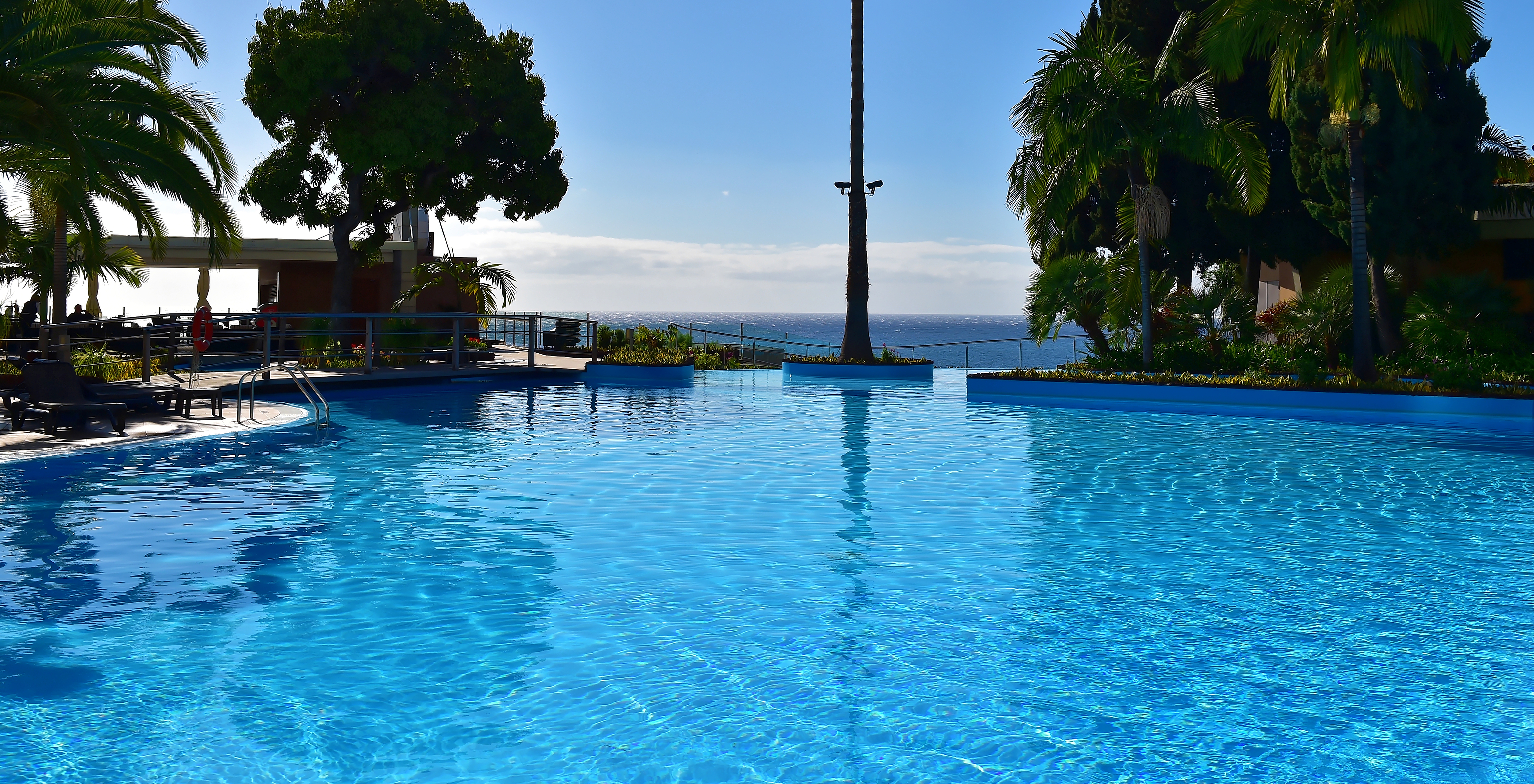 Piscina do Pestana Madeira Beach Club, um Hotel no Centro do Funchal, na Madeira, com árvores à volta e vista para o mar