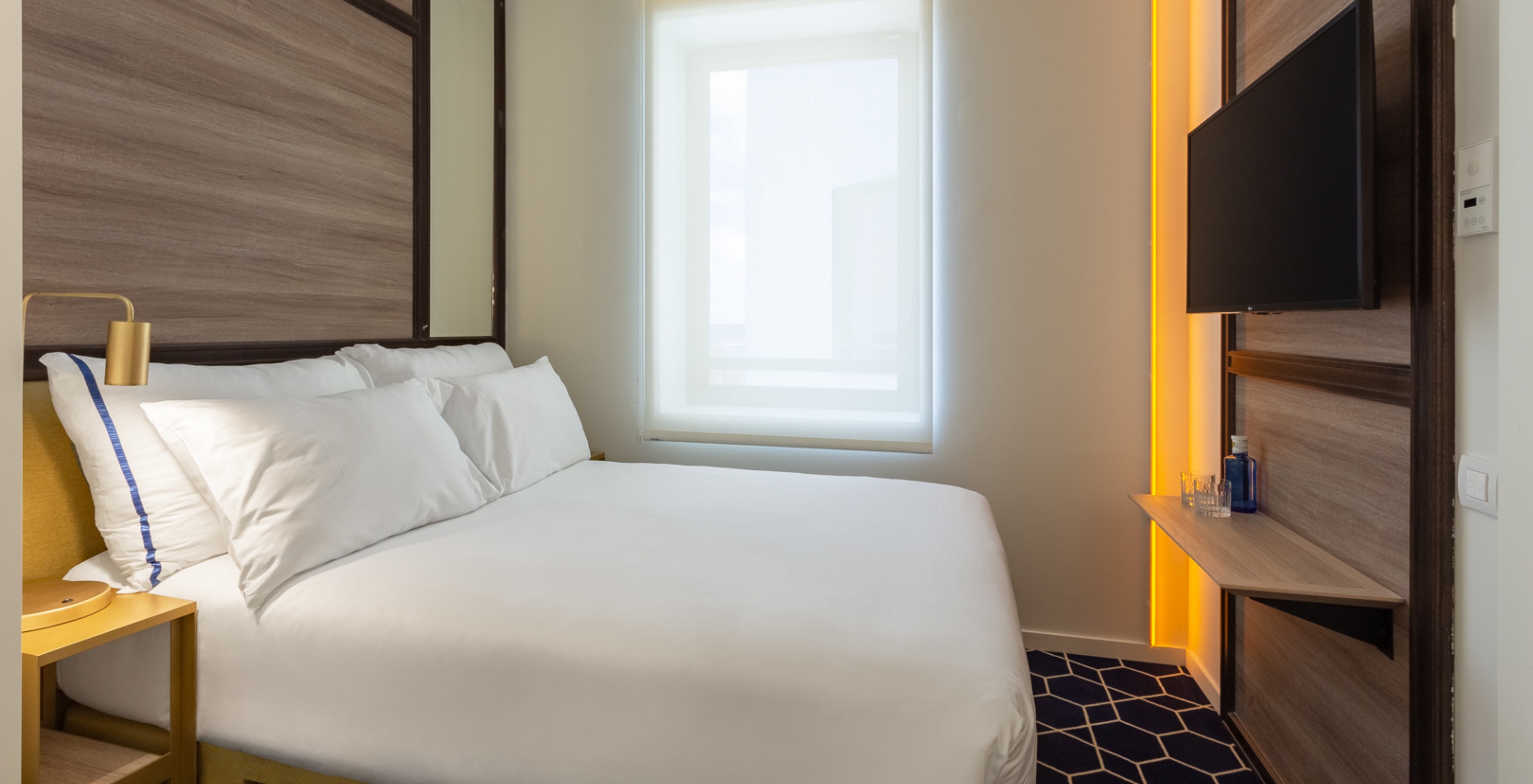 O Small Double Room do Pestana CR7 Gran Vía Madrid tem uma cama de casal, uma janela e uma mesa de cabeceira amarela