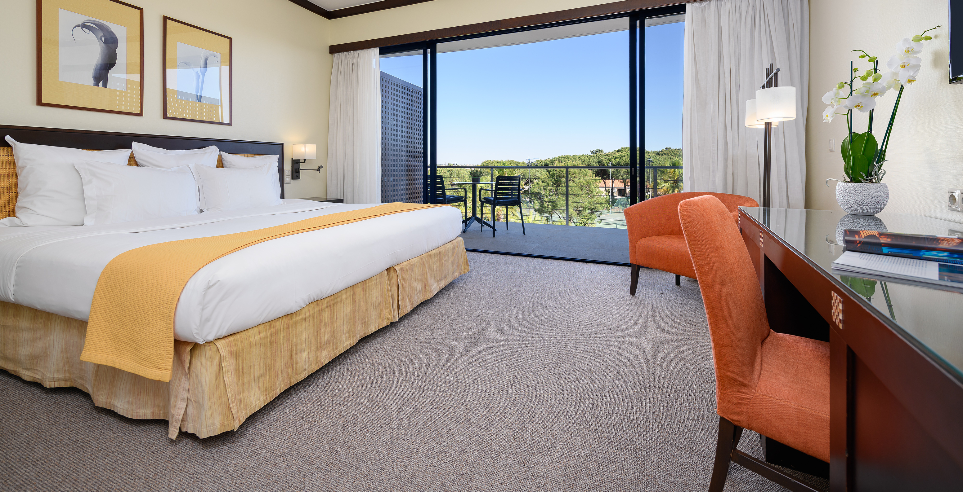 A Suite Vista Jardim Vila Sol do Pestana Vila Sol - Vilamoura tem uma cama de casal, varanda, secretária e duas cadeiras laranja