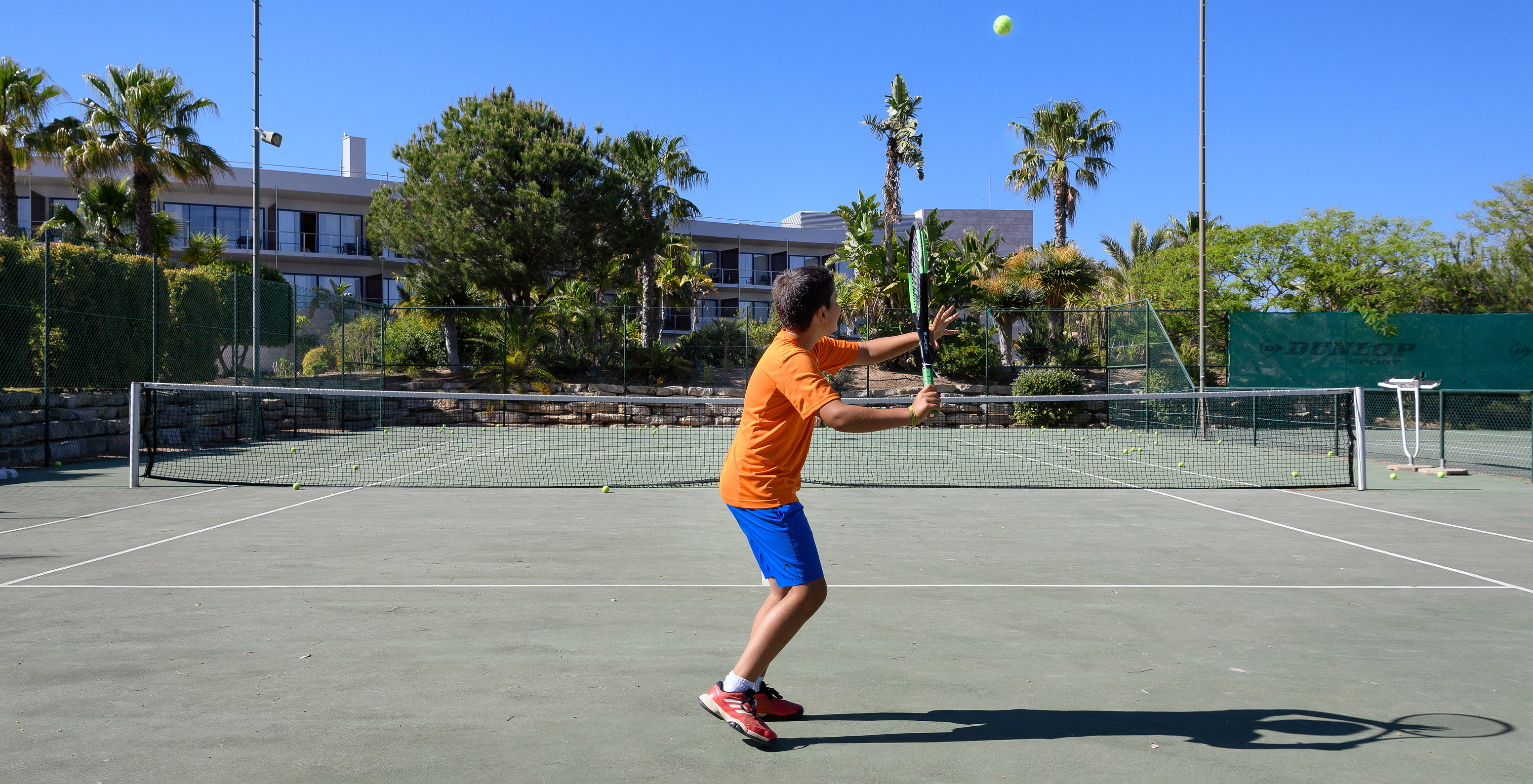 Criança a jogar ténis no campo de ténis do Pestana Vila Sol - Vilamoura, Hotel com Golfe e Spa no Algarve