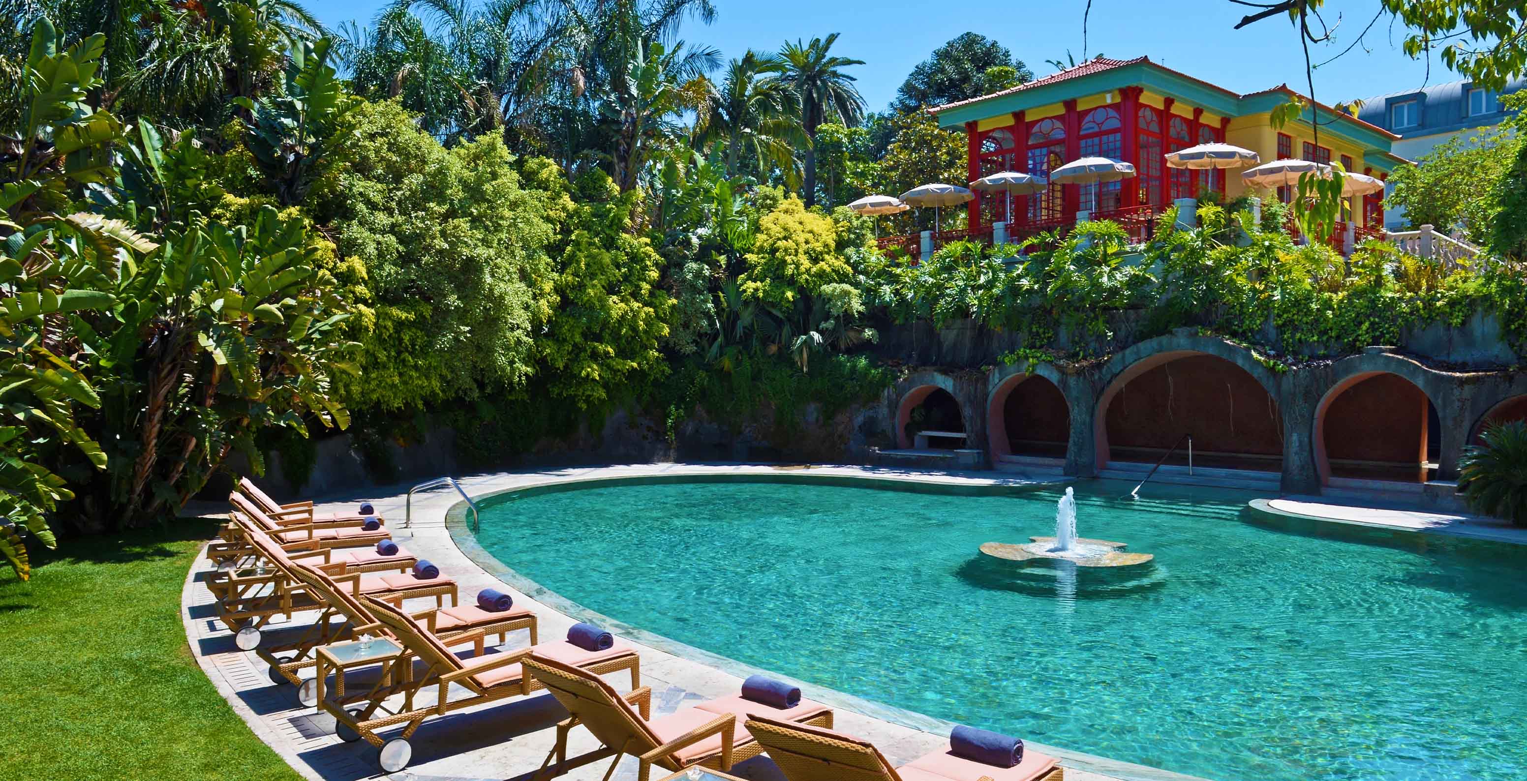 Piscina exterior com uma fonte central e espreguiçadeiras no Palace Lisboa, Hotel num Palácio em Lisboa, com Piscinas e Spa