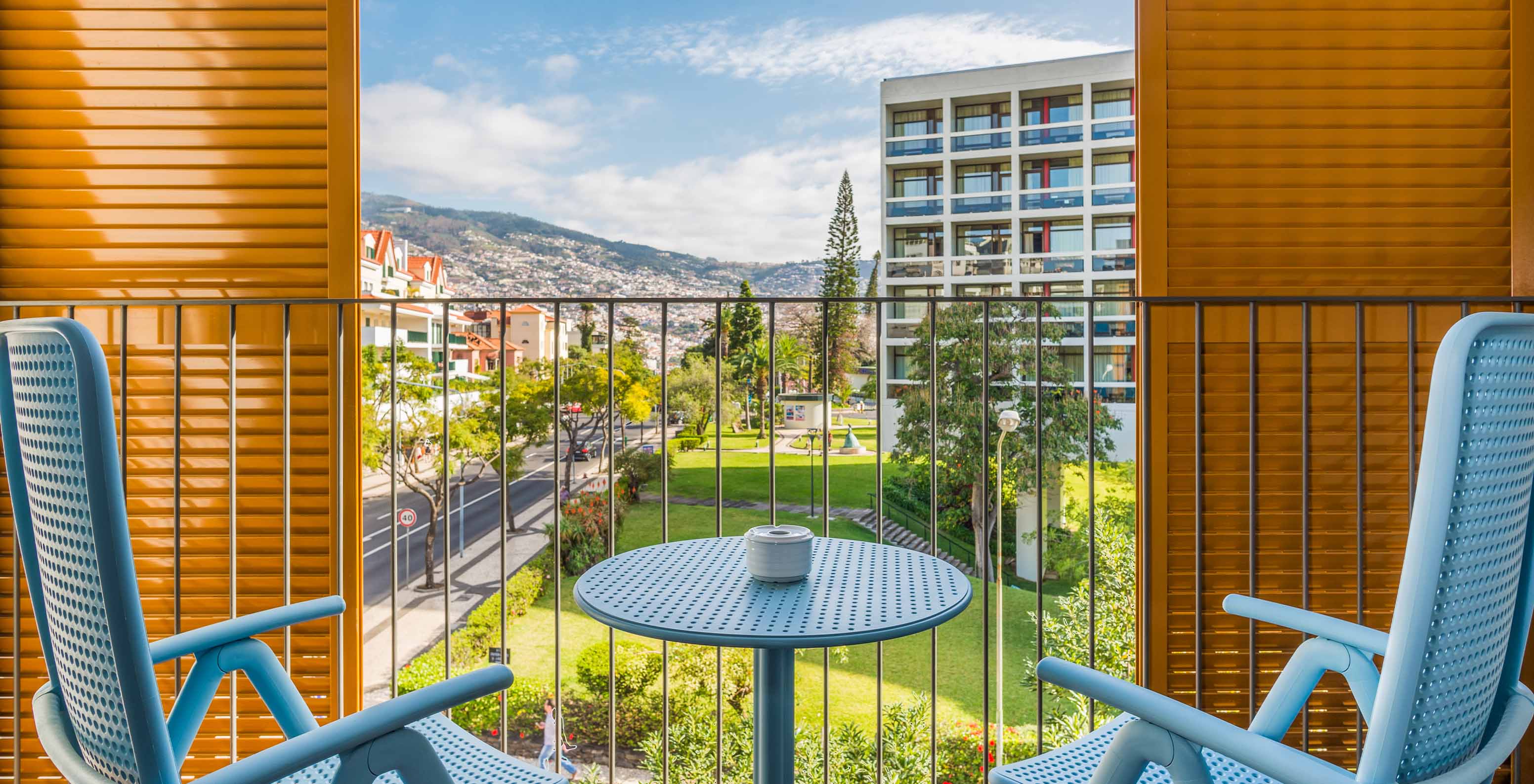 O Estúdio Deluxe do Pestana Casino Studios tem uma varanda com vista para a cidade e uma mesa com cadeiras azuis