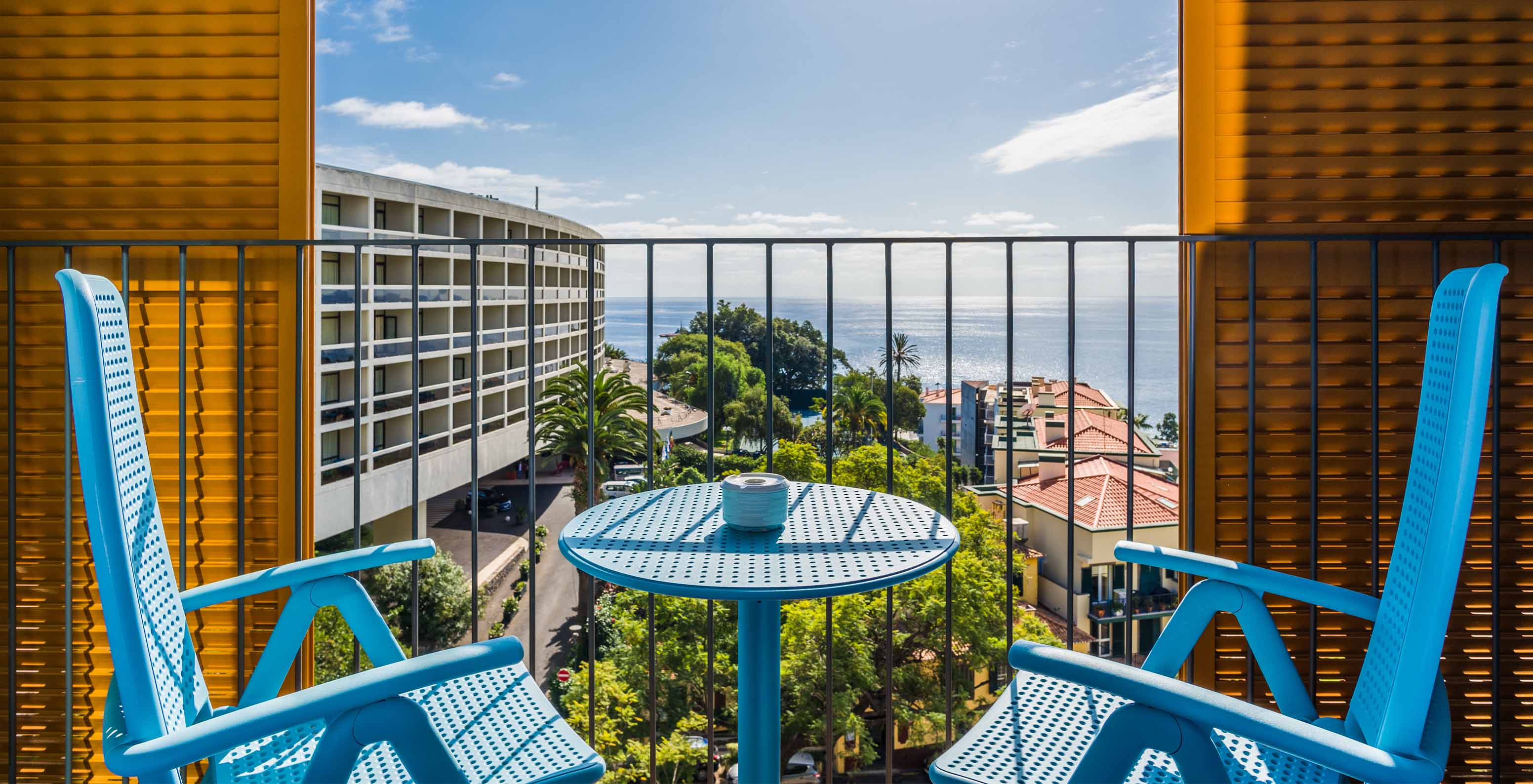 O Estúdio Deluxe Vista Mar do Pestana Casino Studios tem uma varanda com vista para a cidade e uma mesa com cadeiras azuis