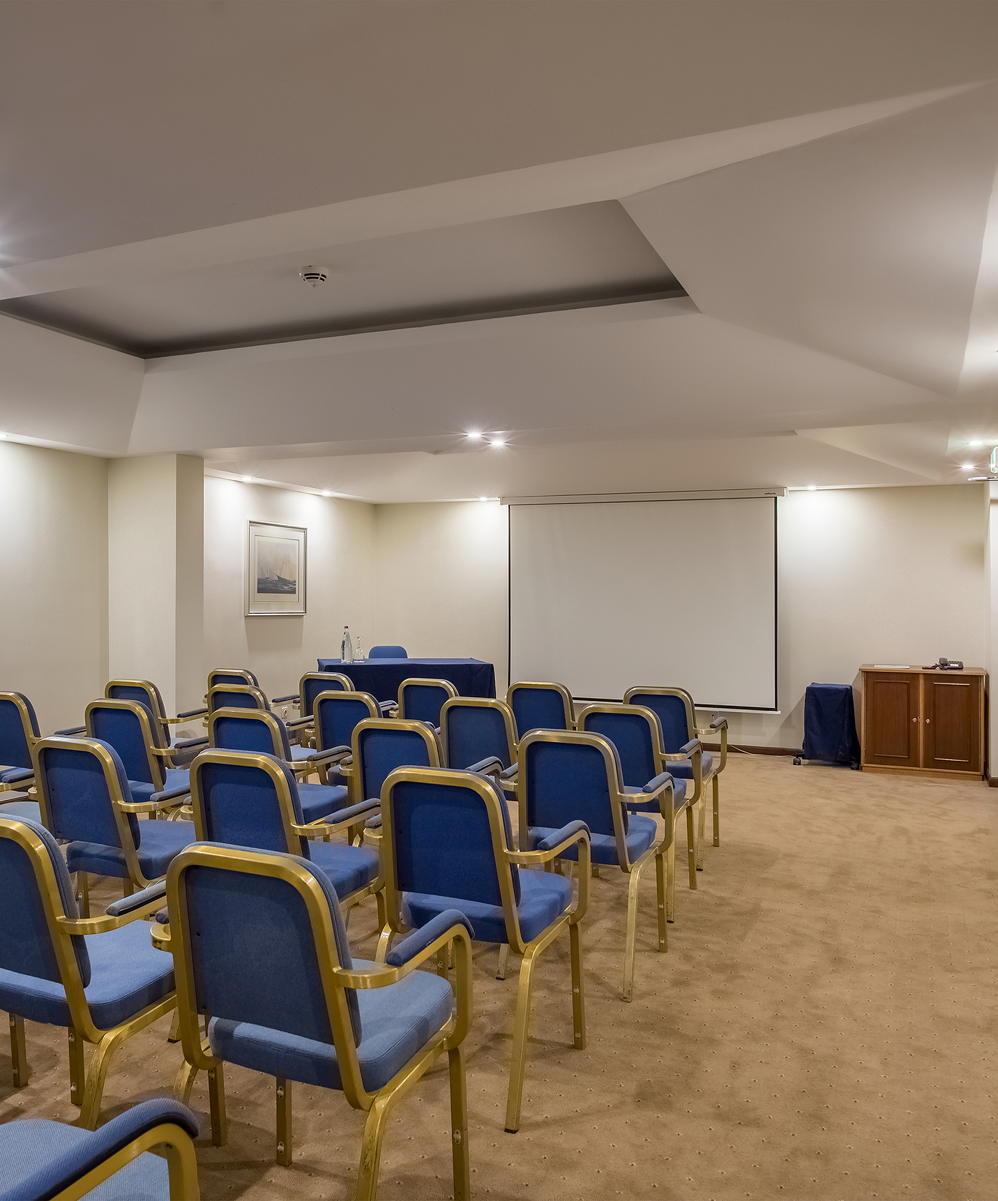 Sala de Reuniões com várias cadeiras azuis voltadas para um projetor, no Pestana Village, um Hotel Romântico no Funchal