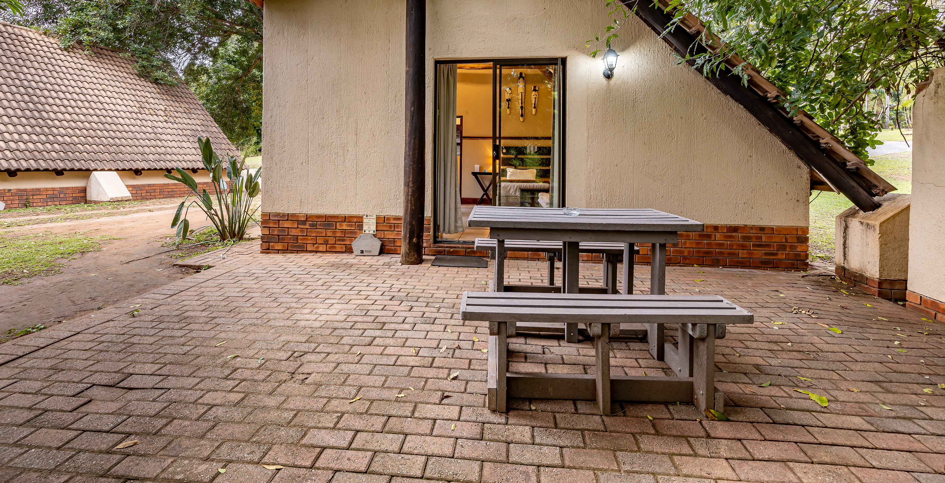 O Quarto Familiar do Pestana Kruger Lodge tem uma zona exterior com uma mesa corrida de madeira, com vista para o jardim