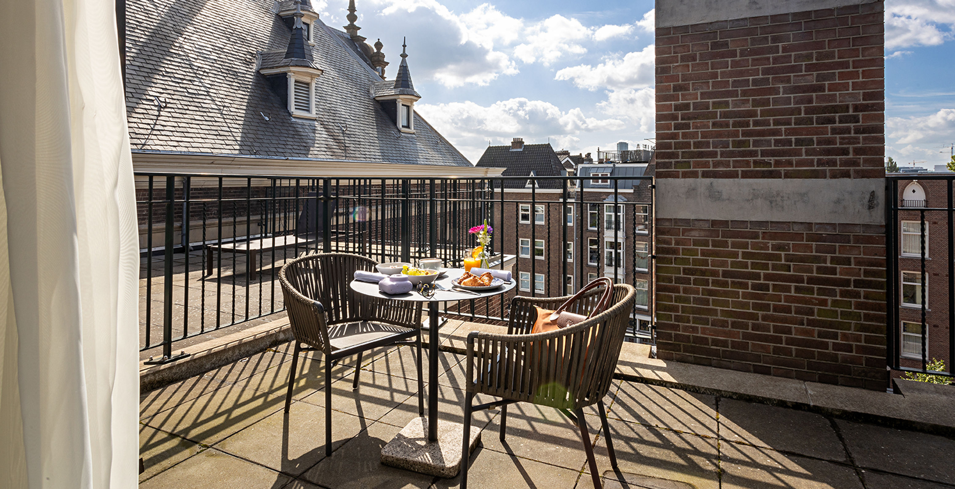 O quarto Executive Terrace do Pestana Amsterdam Riverside tem uma varanda, com uma mesa com comida, e duas cadeiras