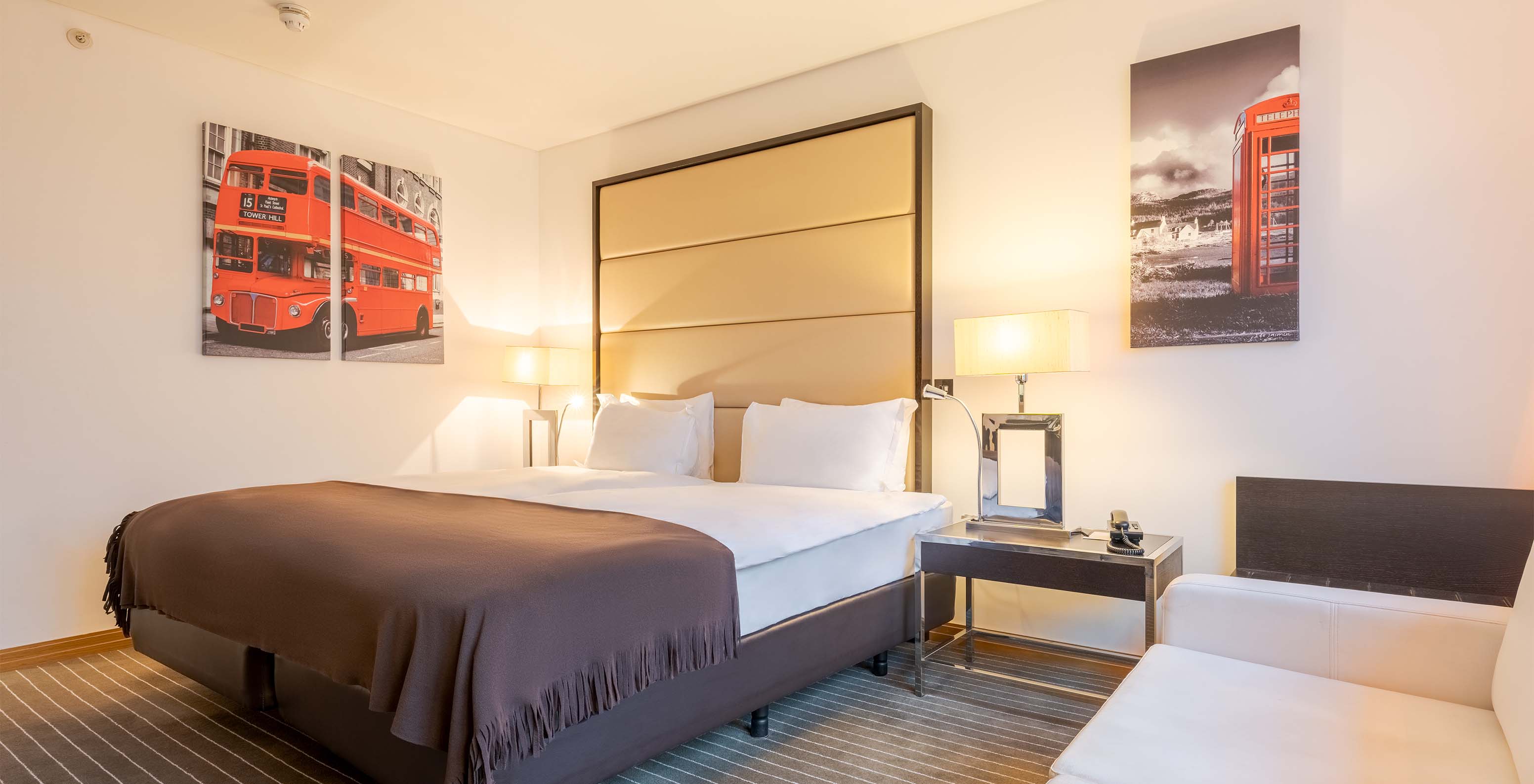 O Deluxe Superior King do Pestana Chelsea Bridge tem cama de casal com quadros de Londres, mesa de cabeceira e sofá