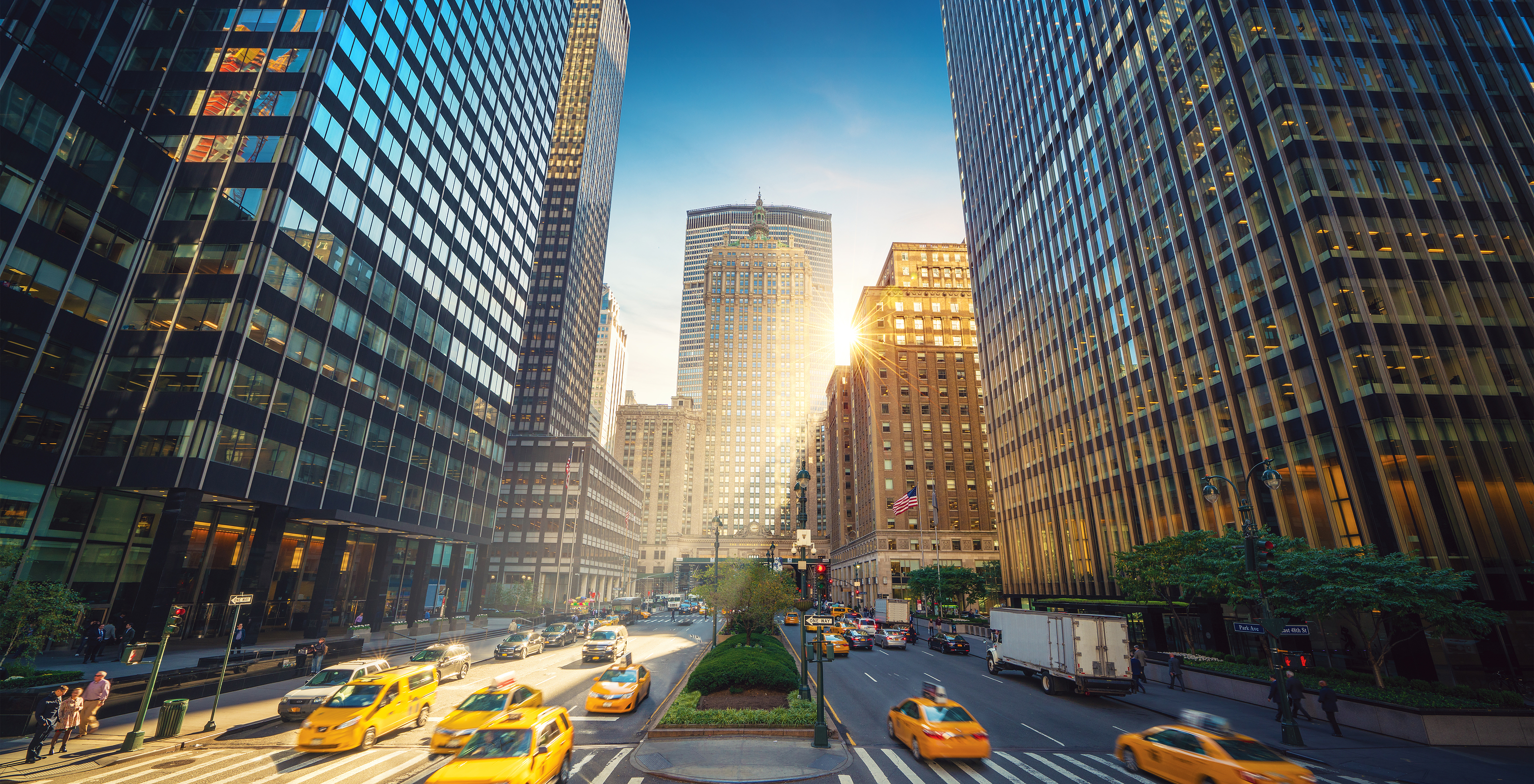 Vista panorâmica da Fifth Avenue em Manhattan, Nova York, com arranha-céus imponentes ao fundo e táxis amarelos